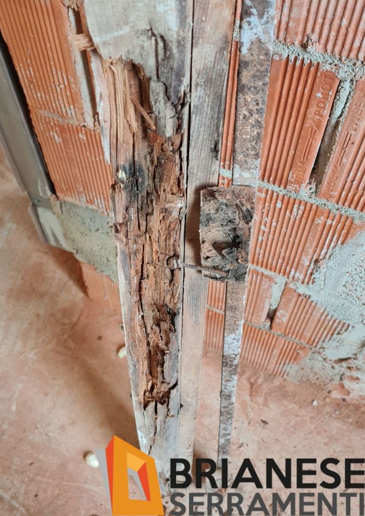 Telaio in legno di una porta completamente marcio nella parte a contatto con la muratura.